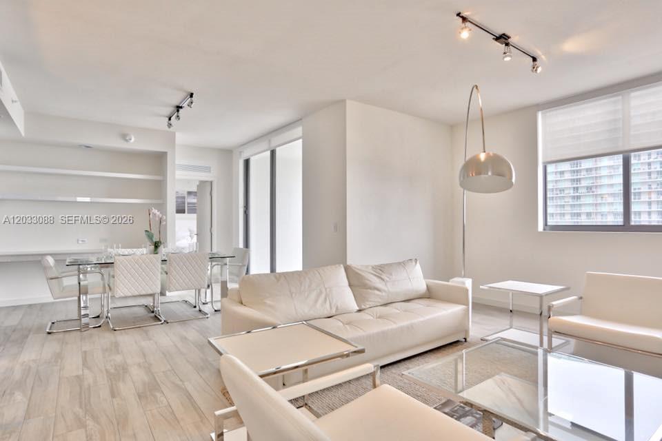 A bright, modern living and dining area features white furniture, glass tables, and tile flooring — 999 SW 1st Ave # 2404, Miami FL 33130, MIAMI, FL