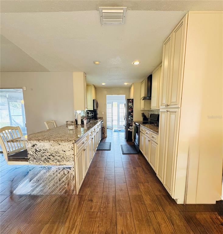 A kitchen features cream-colored cabinets, granite countertops, and wood-look tile flooring — 1221 LEEWAY AVENUE, ORLANDO, FL