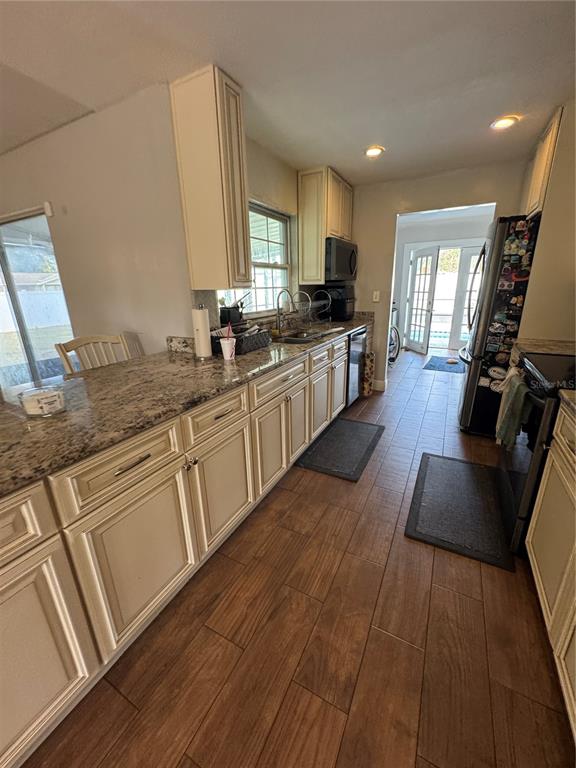 A kitchen features granite countertops, cream-colored cabinets, and wood-look tile flooring — 1221 LEEWAY AVENUE, ORLANDO, FL