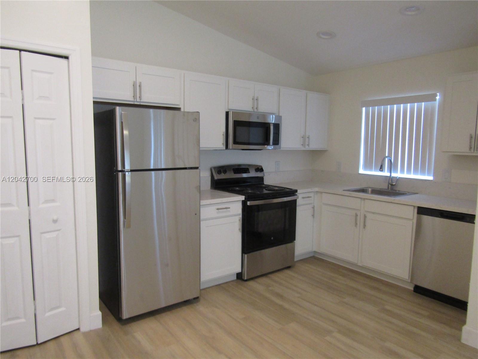 A kitchen features white cabinets, stainless steel appliances, and light wood-look flooring — 4525 28 ST SW # 4525, Lehigh Acres FL 33973, LEHIGH ACRES, FL