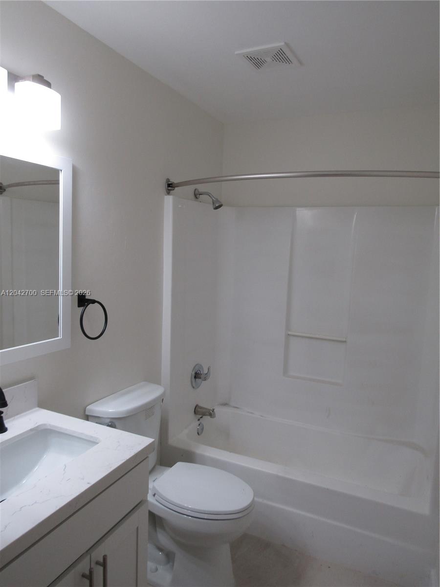 A bathroom features a white vanity, a toilet, and a shower-tub combination with white walls — 4525 28 ST SW # 4525, Lehigh Acres FL 33973, LEHIGH ACRES, FL