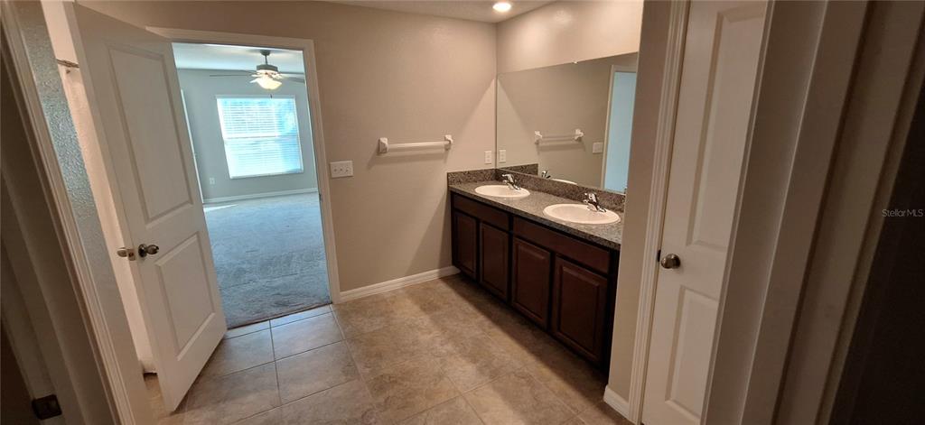 A bathroom features a double-sink vanity with dark cabinets, a large mirror, and tile flooring — 39934 DAWSON CHASE DRIVE, ZEPHYRHILLS, FL