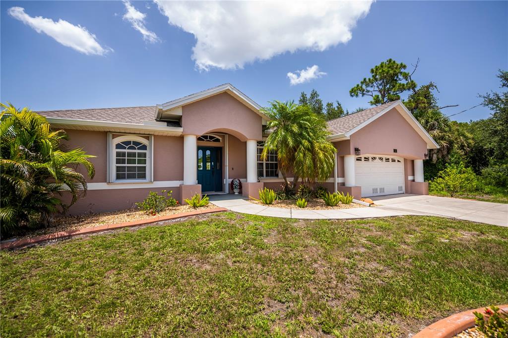 A single-story house with a tan stucco exterior, a two-car garage, and a front walkway — 113 & 121 RED CEDAR PARK, ROTONDA WEST, FL