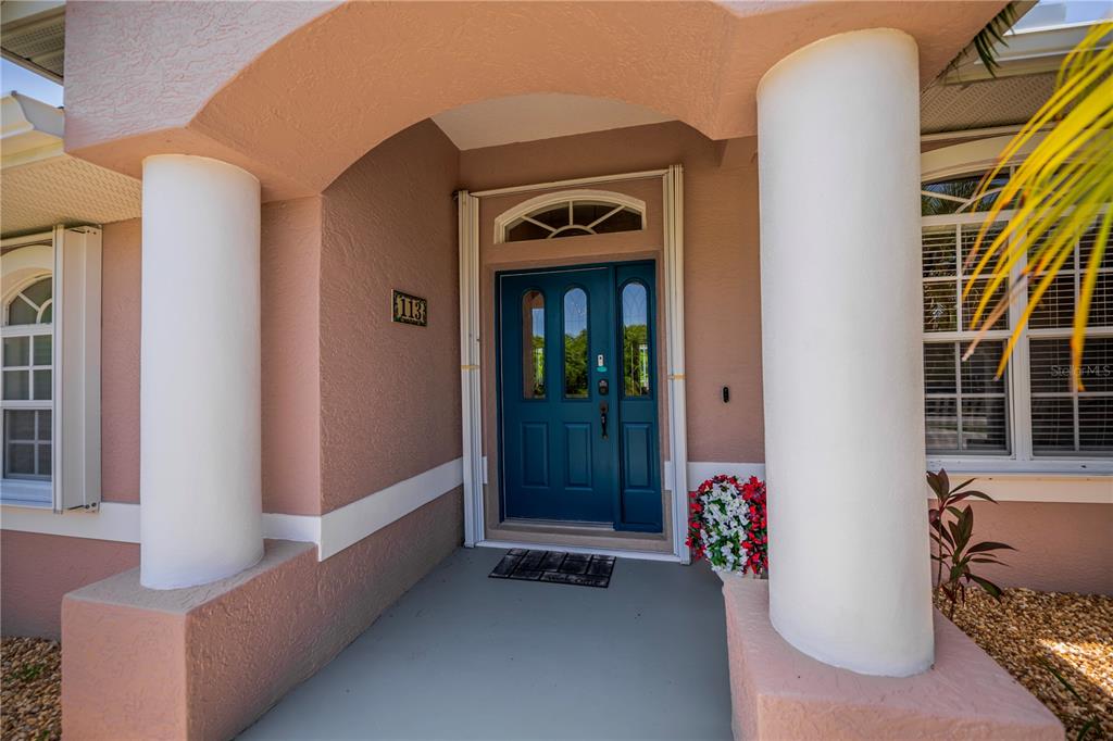 A blue front door is framed by two white columns on a covered porch — 113 & 121 RED CEDAR PARK, ROTONDA WEST, FL