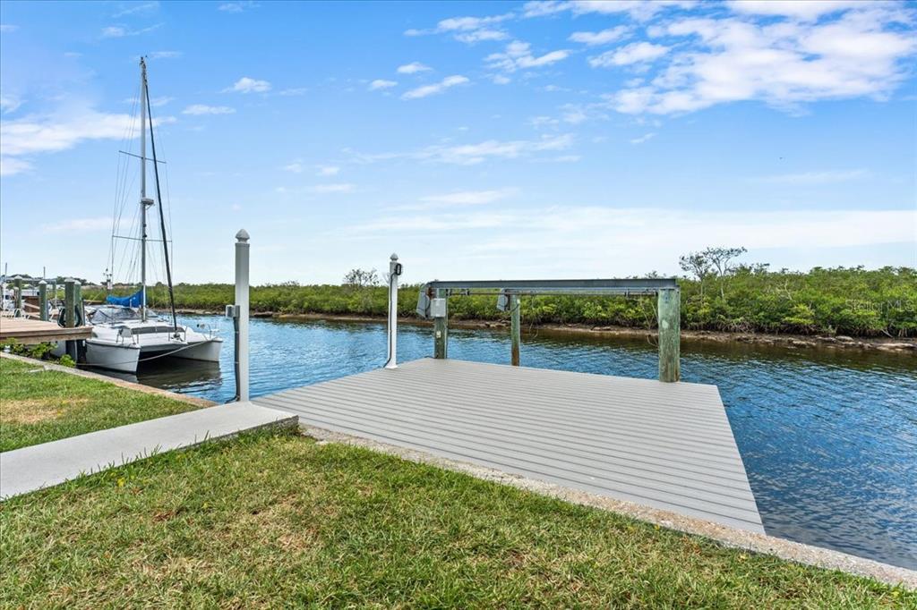 A gray composite boat dock sits along a canal with a sailboat moored nearby — 4147 MARINE PARKWAY, NEW PORT RICHEY, FL