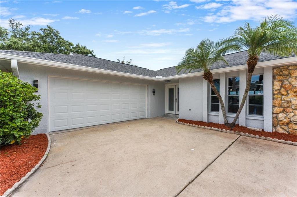 A single-story house exterior features a two-car garage, a front entrance, and two palm trees — 4147 MARINE PARKWAY, NEW PORT RICHEY, FL