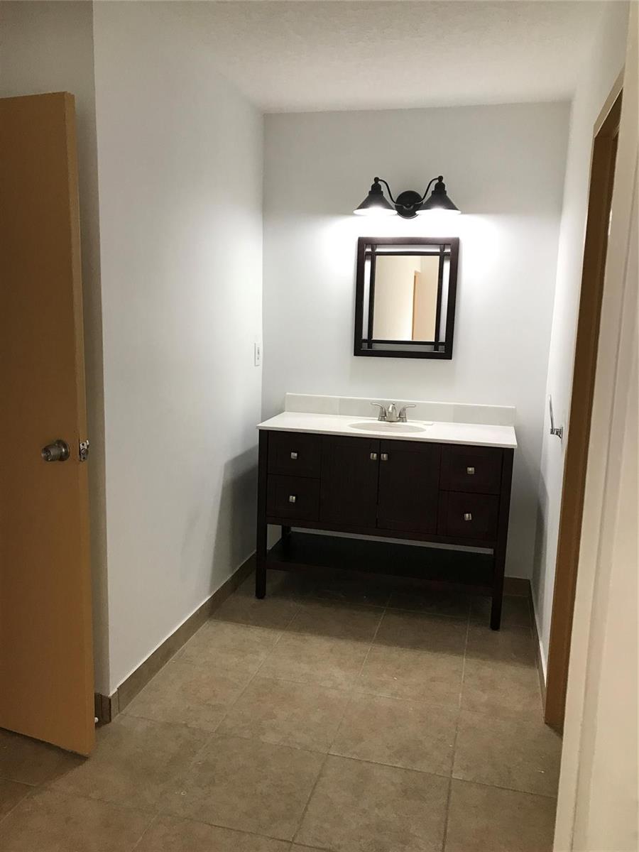 A bathroom features a dark wood vanity with a white countertop and a framed mirror — 4394 NW 9th Avenue # 3a, Deerfield Beach FL 33064, DEERFIELD BEACH, FL