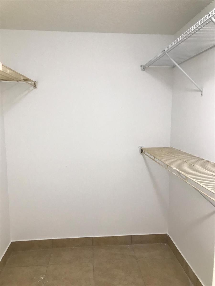 A walk-in closet with white walls, tile flooring, and white wire shelving — 4394 NW 9th Avenue # 3a, Deerfield Beach FL 33064, DEERFIELD BEACH, FL