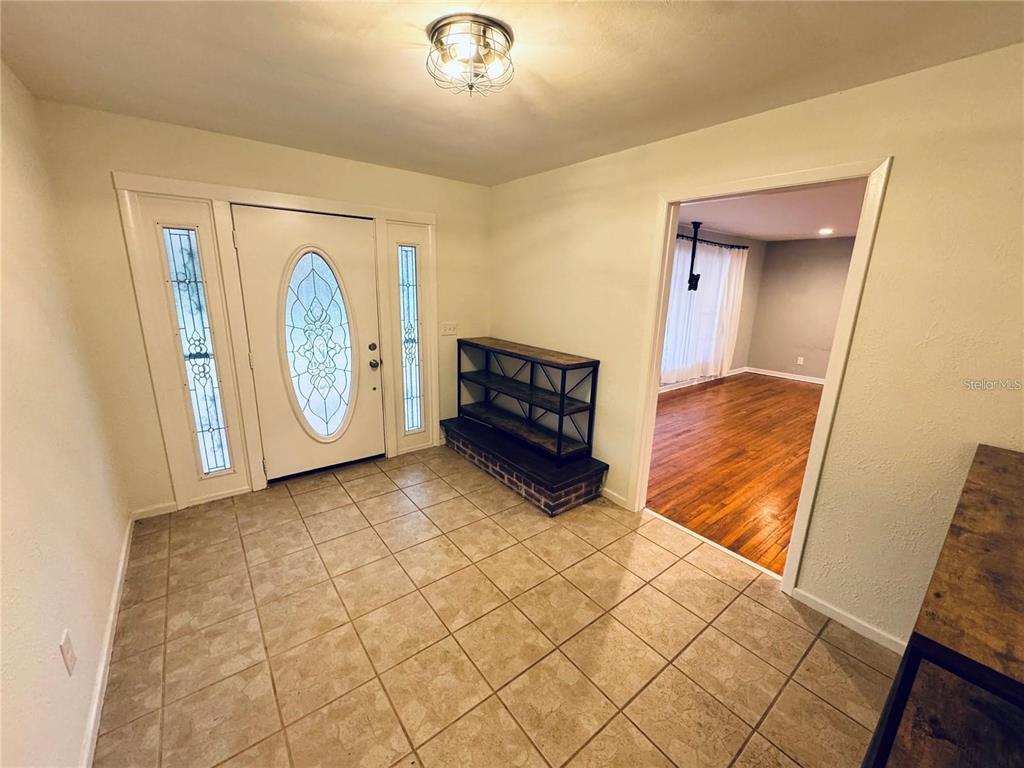 An entryway with tile flooring, a white front door with sidelights, and a wooden bench — 2022 EDGEWOOD ROAD, LEESBURG, FL