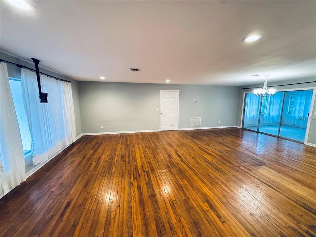 A spacious room features hardwood floors, light blue walls, a white door, and sliding doors — 2022 EDGEWOOD ROAD, LEESBURG, FL