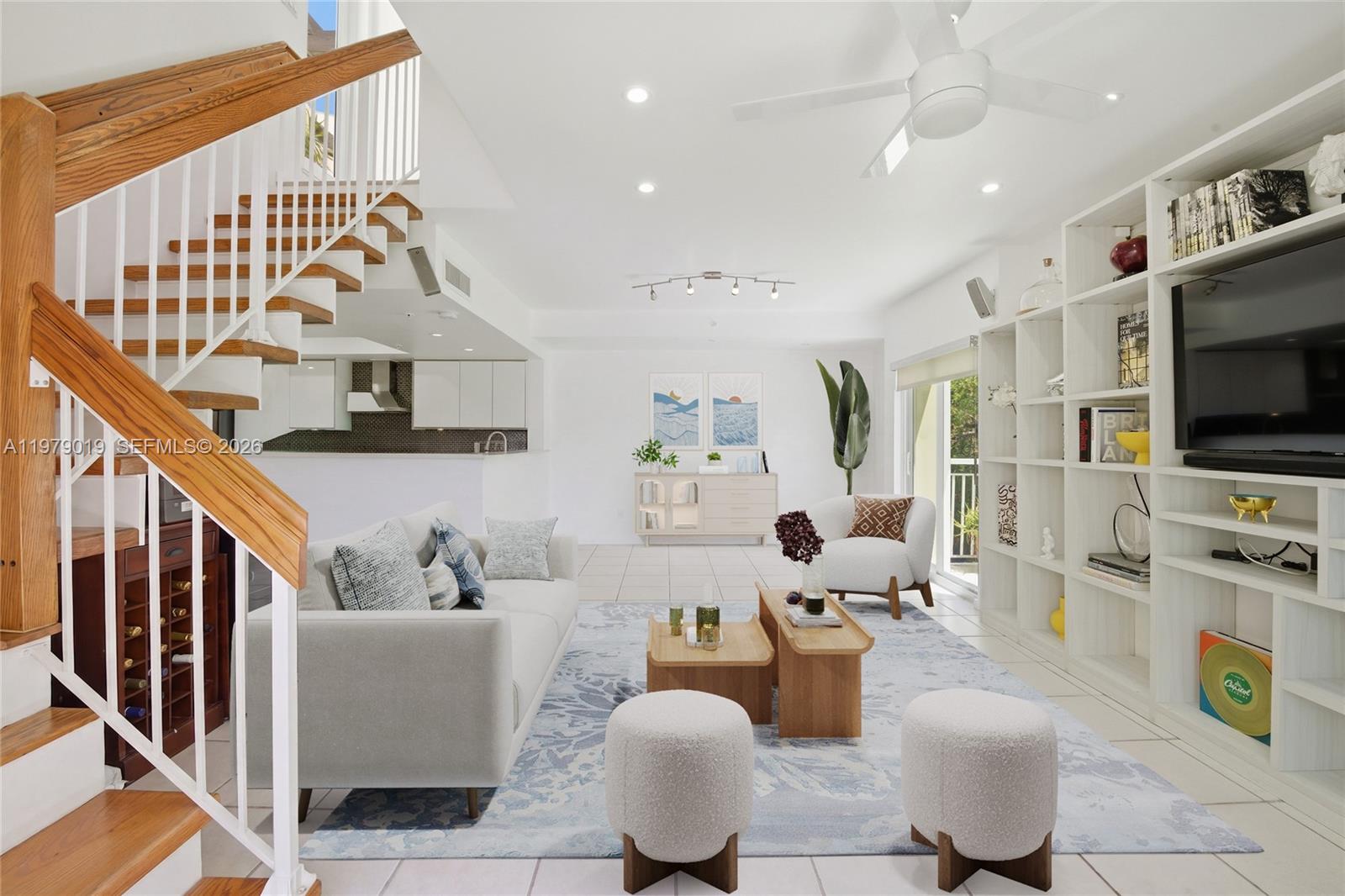 A bright living room features a white sofa, two ottomans, and a large built-in bookshelf — 120 Jefferson Ave # 12022, Miami Beach FL 33139, MIAMI BEACH, FL