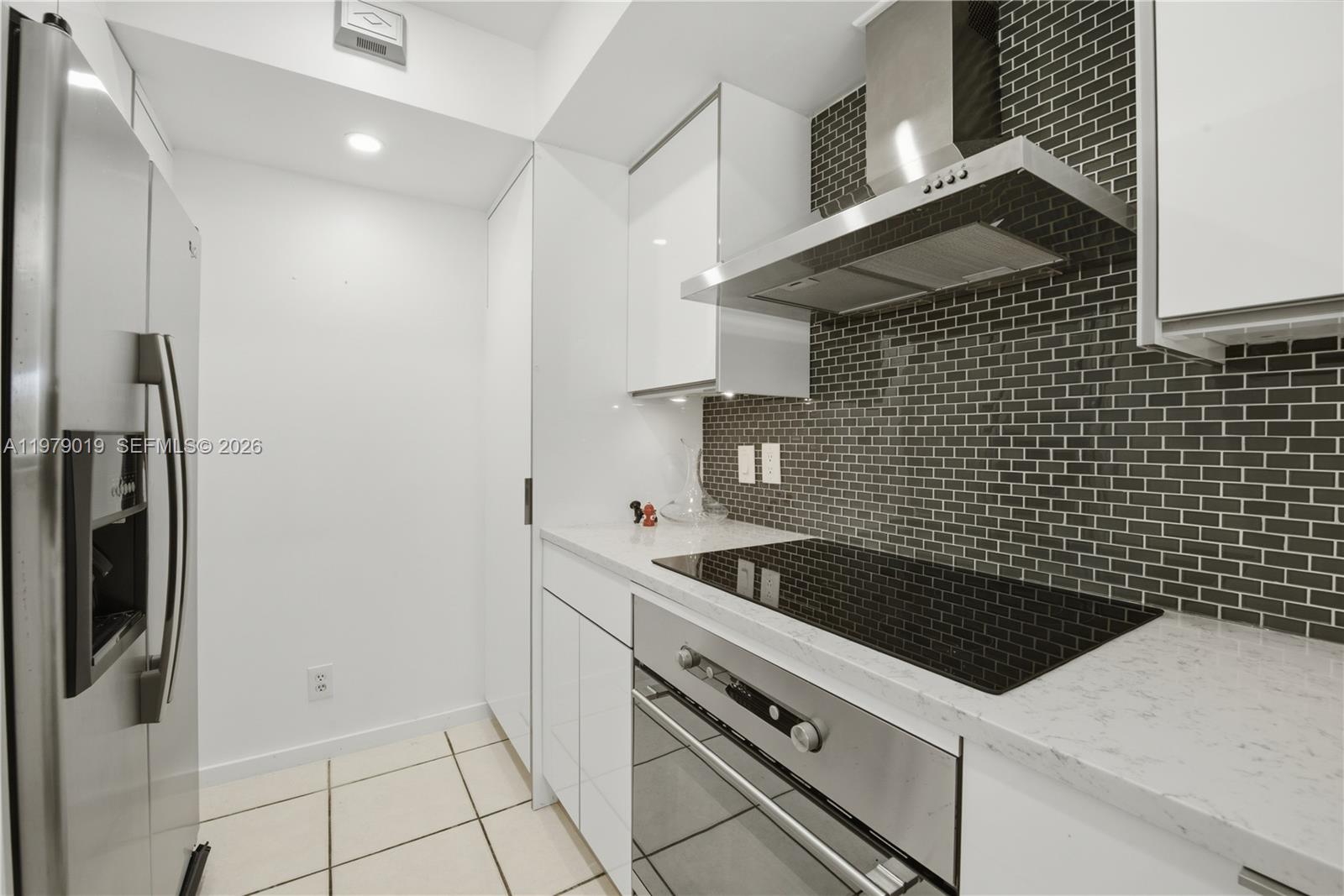 A modern kitchen features white cabinets, a stainless steel oven, and a dark tiled backsplash — 120 Jefferson Ave # 12022, Miami Beach FL 33139, MIAMI BEACH, FL