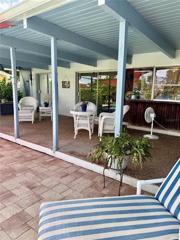 A covered patio features white wicker furniture, a small table, and a blue-striped lounge chair — 17109 RAINBOW TERRACE, ODESSA, FL