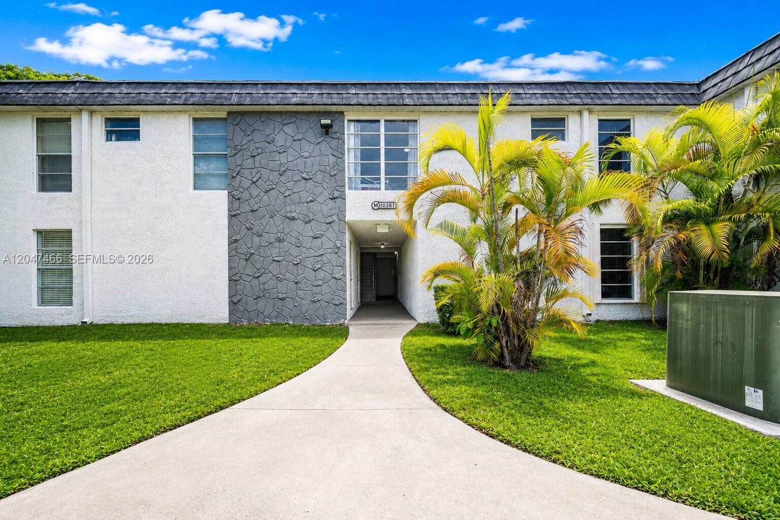 A two-story apartment building exterior features white stucco walls, gray stone accents, and palm trees — 10381 N Kendall Dr # M8, Miami FL 33176, MIAMI, FL