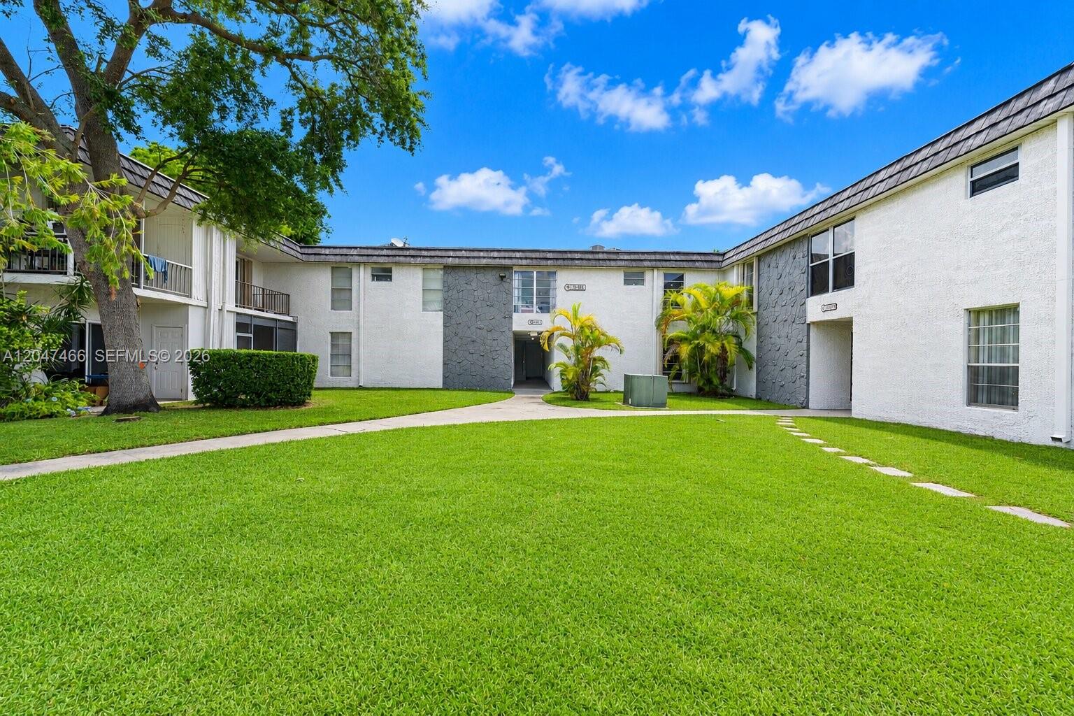 A two-story apartment building with white stucco walls and gray stone accents faces a lawn — 10381 N Kendall Dr # M8, Miami FL 33176, MIAMI, FL