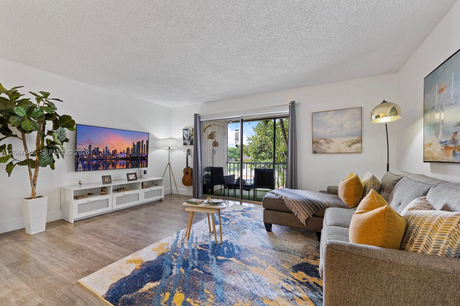 A living room features a gray sectional sofa, a patterned area rug, and a balcony — 10381 N Kendall Dr # M8, Miami FL 33176, MIAMI, FL