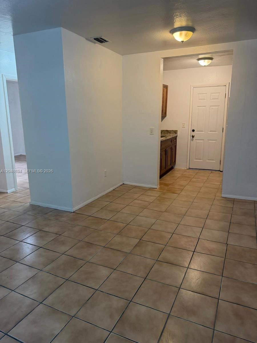 This interior view shows a tiled room leading to a doorway and a small vanity — 1019 NW 52nd St # A, Miami FL 33127, MIAMI, FL