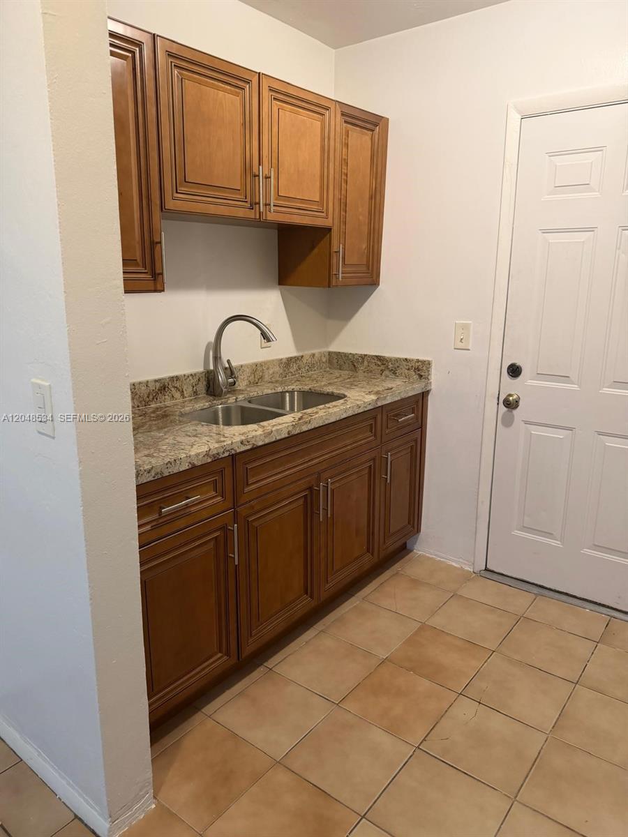 A kitchen features wooden cabinets, a granite countertop, and a stainless steel sink — 1019 NW 52nd St # A, Miami FL 33127, MIAMI, FL