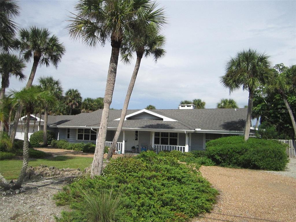 A single-story house with a gray roof and white trim surrounded by palm trees — 3534 CASEY KEY ROAD, NOKOMIS, FL