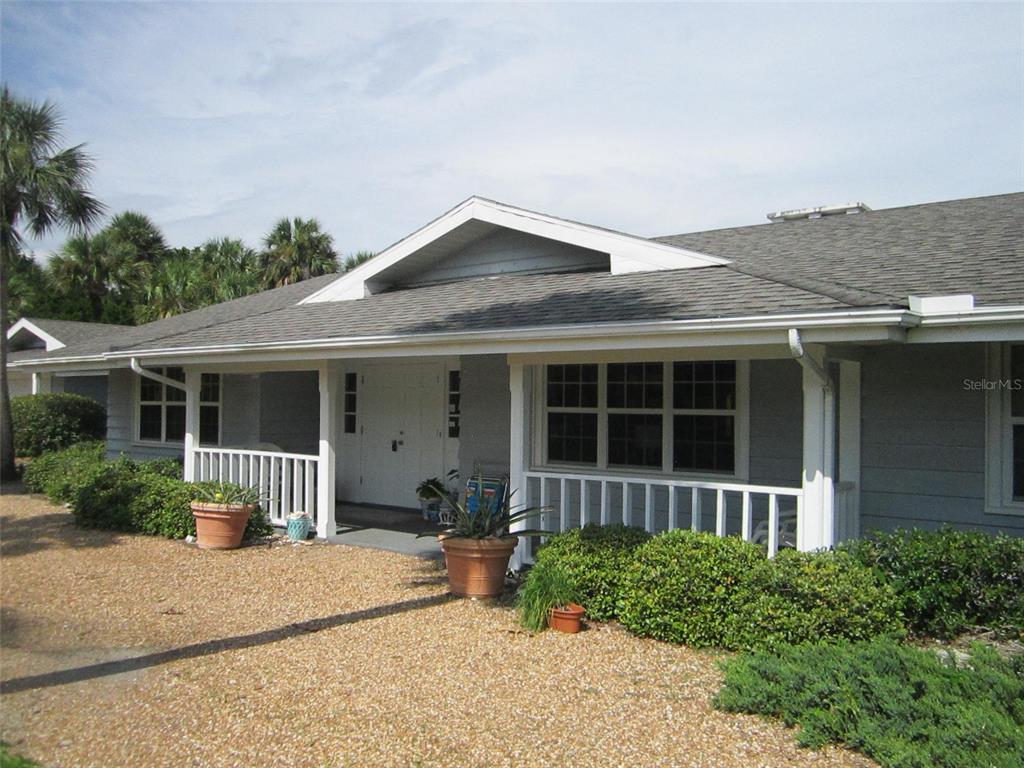 A single-story house with a grey exterior, a covered porch, and a gravel front yard — 3534 CASEY KEY ROAD, NOKOMIS, FL
