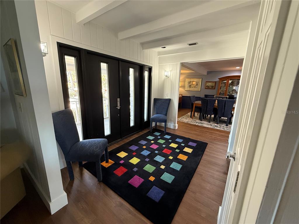 An entryway features a colorful patterned rug, two blue chairs, and dark double doors — 3534 CASEY KEY ROAD, NOKOMIS, FL
