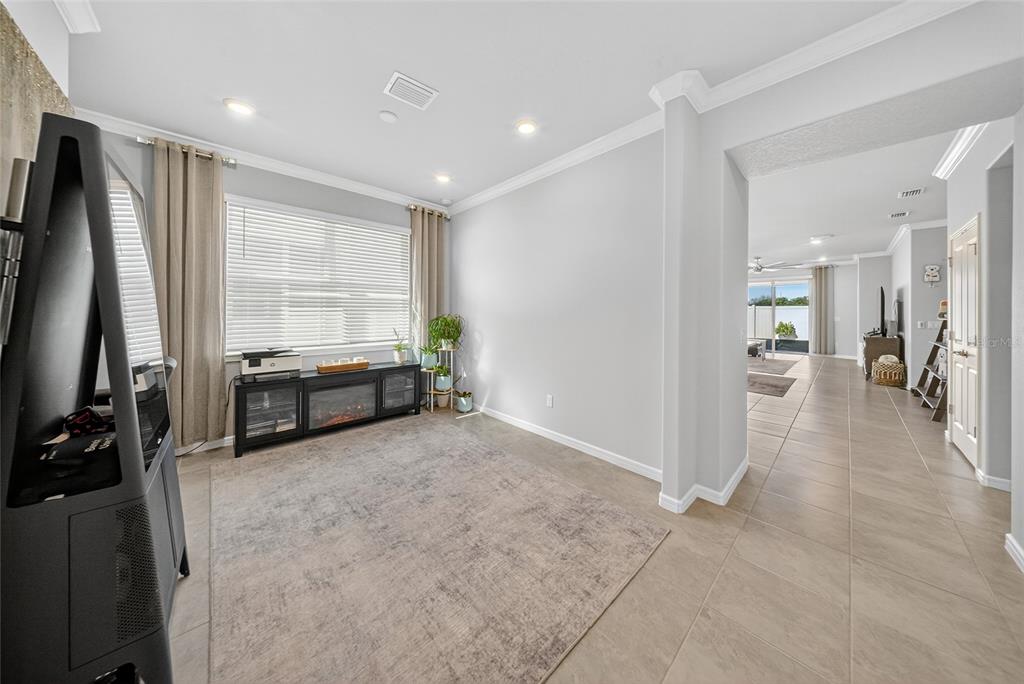 A room with light gray walls, tile flooring, a large window, and a media console — 1845 SPRING SHOWER CIRCLE, KISSIMMEE, FL
