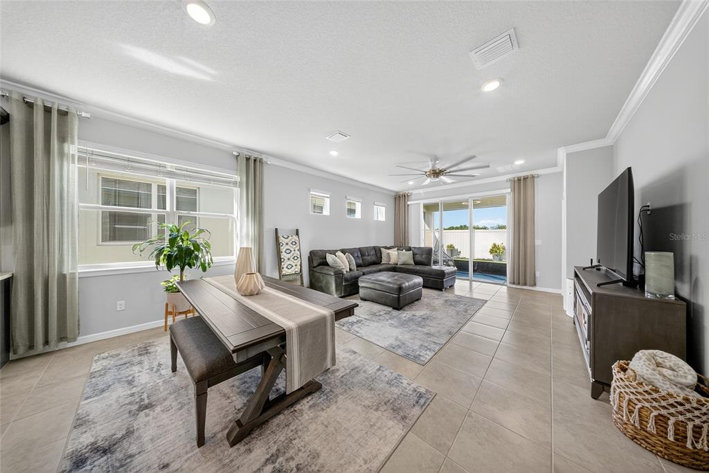 A spacious open-concept living room features a large sectional sofa, dining area, and kitchen — 1845 SPRING SHOWER CIRCLE, KISSIMMEE, FL