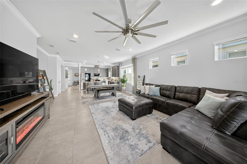 A living room with a brown sectional sofa, television, fireplace, and an open kitchen area — 1845 SPRING SHOWER CIRCLE, KISSIMMEE, FL