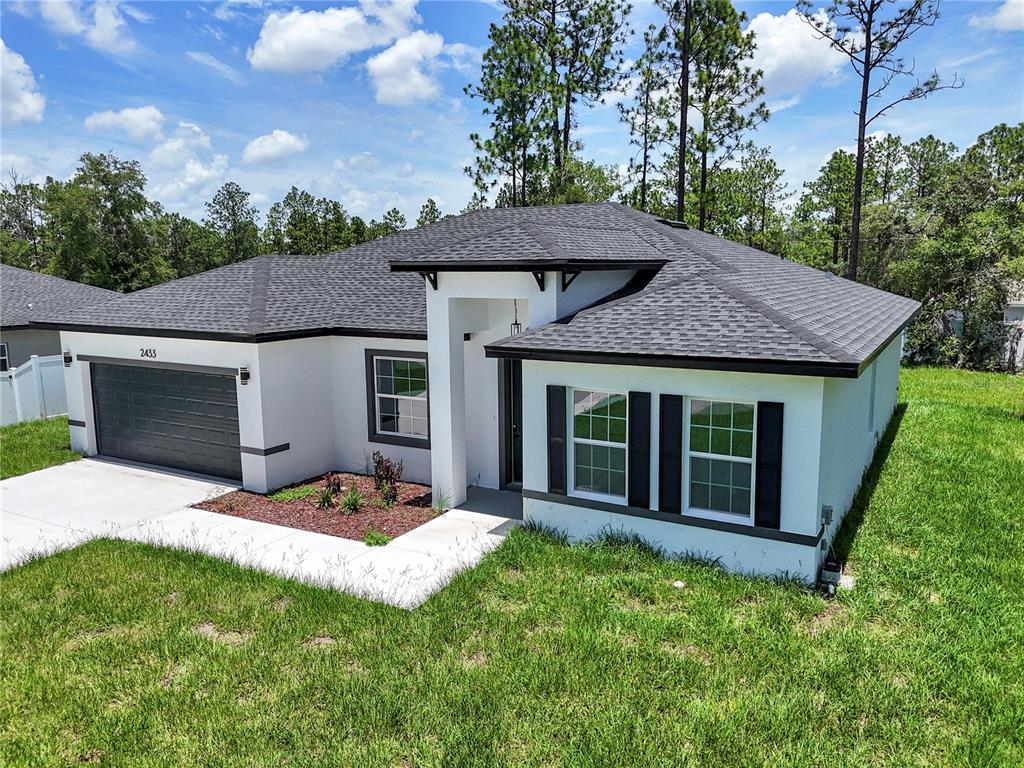 A white single-story house with a dark shingled roof and black window shutters — 2433 W ANDROMEDAE DRIVE, CITRUS SPRINGS, FL
