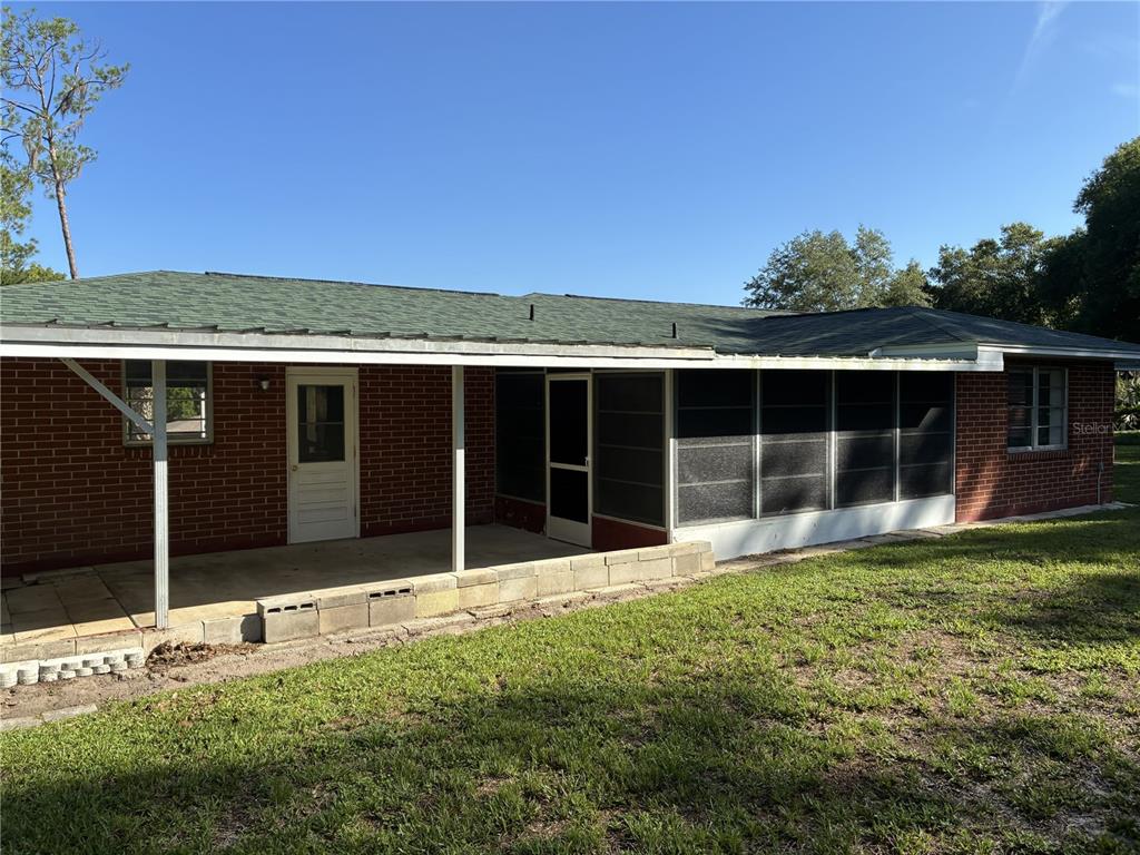 The rear exterior of a brick house features a covered patio and a screened-in porch — 4926 MAGNOLIA RIDGE ROAD, FRUITLAND PARK, FL