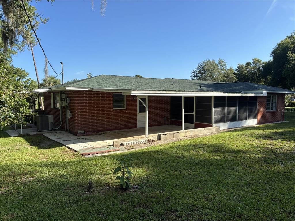 A brick house features a covered patio and an attached screened-in porch in the backyard — 4926 MAGNOLIA RIDGE ROAD, FRUITLAND PARK, FL