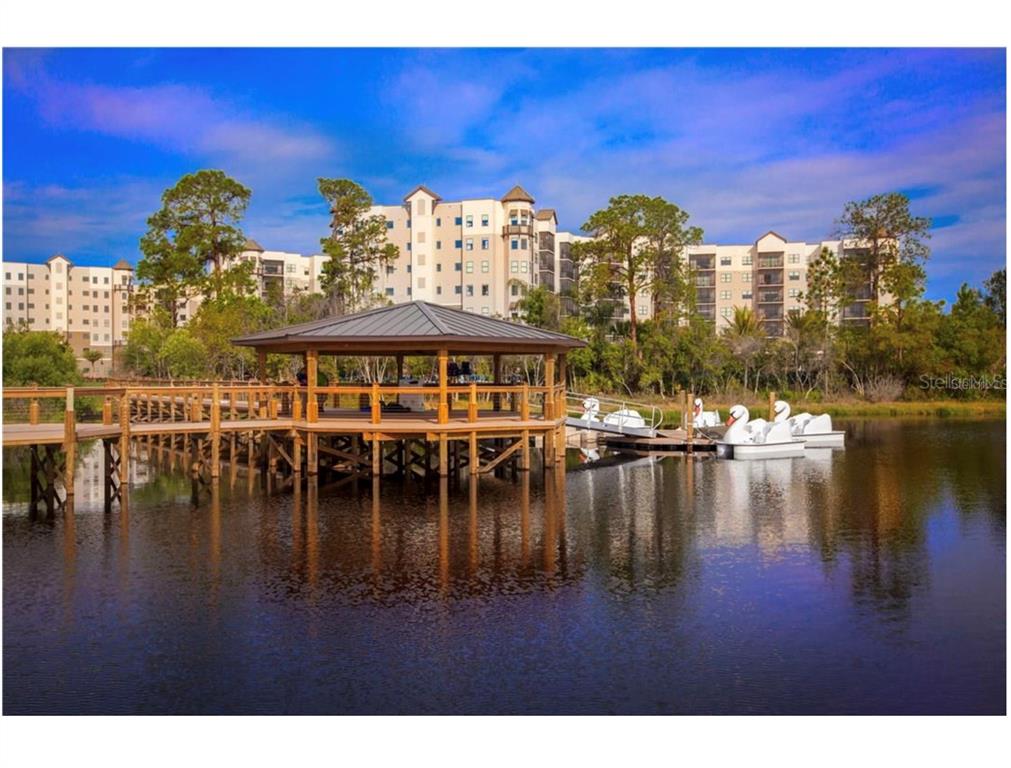 A wooden gazebo sits on a dock over a pond with swan-shaped pedal boats nearby — 14501 GROVE RESORT AVENUE UNIT 1237, WINTER GARDEN, FL
