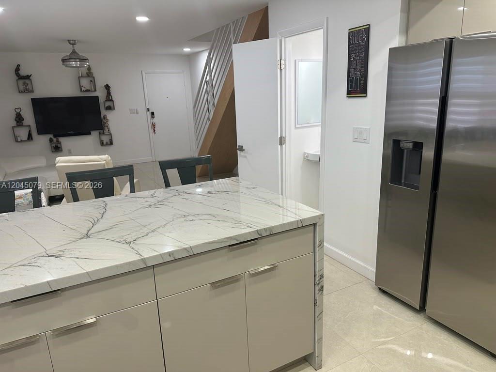 A kitchen island with a marble countertop sits in front of a stainless steel refrigerator — 1560 W 46th St # 228, Hialeah FL 33012, HIALEAH, FL