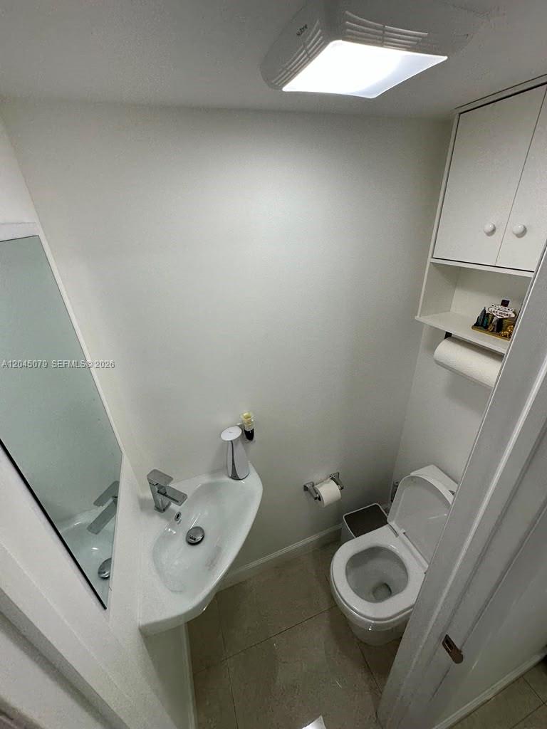 A small bathroom features a white pedestal sink, a toilet, and a wall-mounted storage cabinet — 1560 W 46th St # 228, Hialeah FL 33012, HIALEAH, FL
