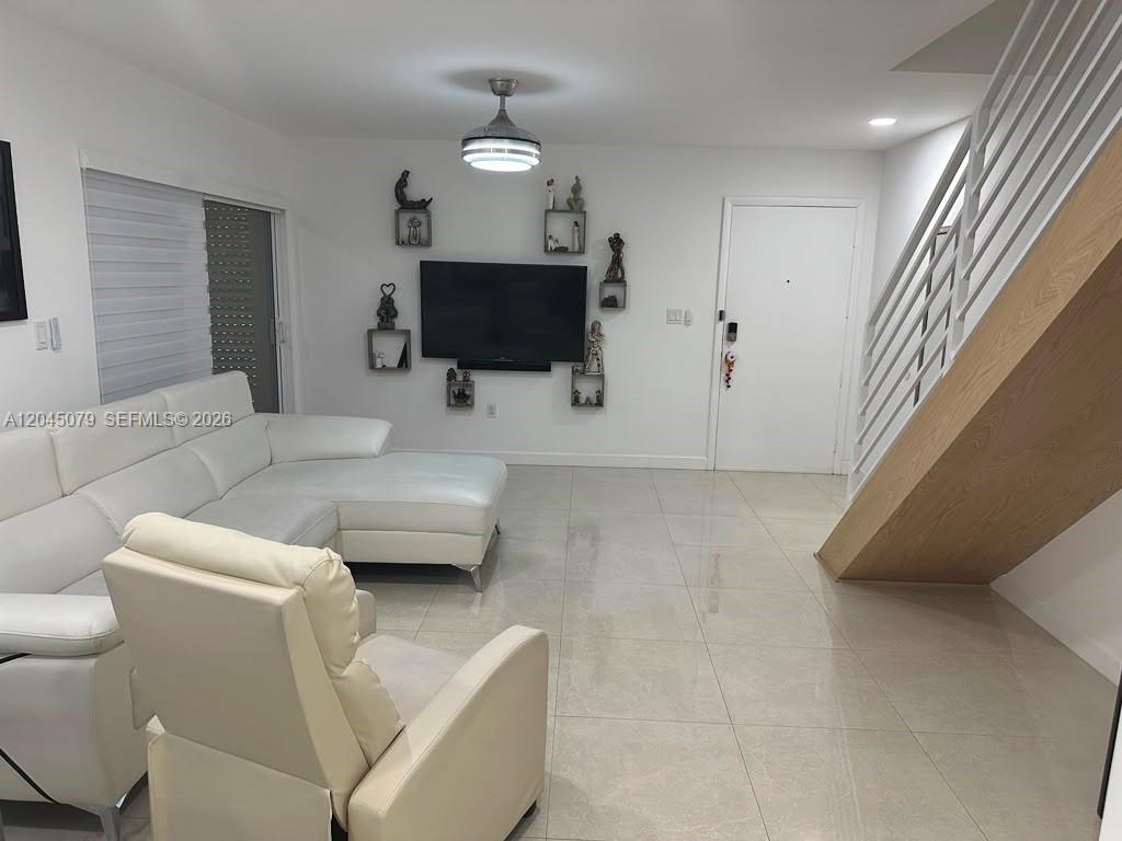 A living room features white tile floors, a sectional sofa, and a staircase — 1560 W 46th St # 228, Hialeah FL 33012, HIALEAH, FL
