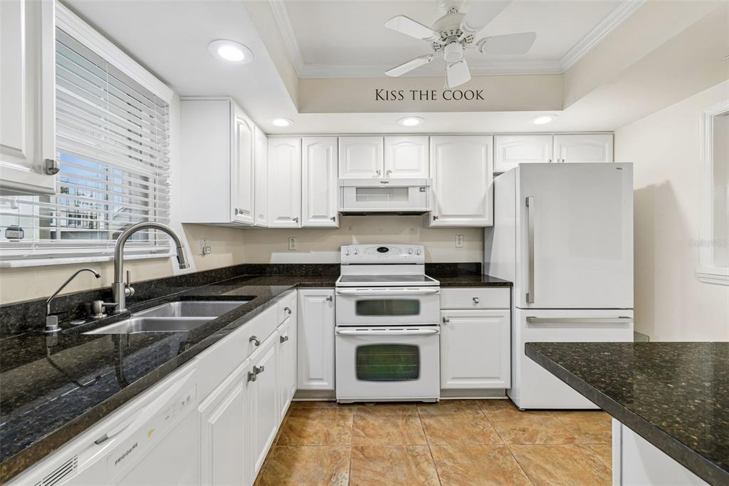 A white kitchen features dark granite countertops, white cabinetry, and a double oven range — 10387 CARROLLWOOD LANE UNIT 303, TAMPA, FL