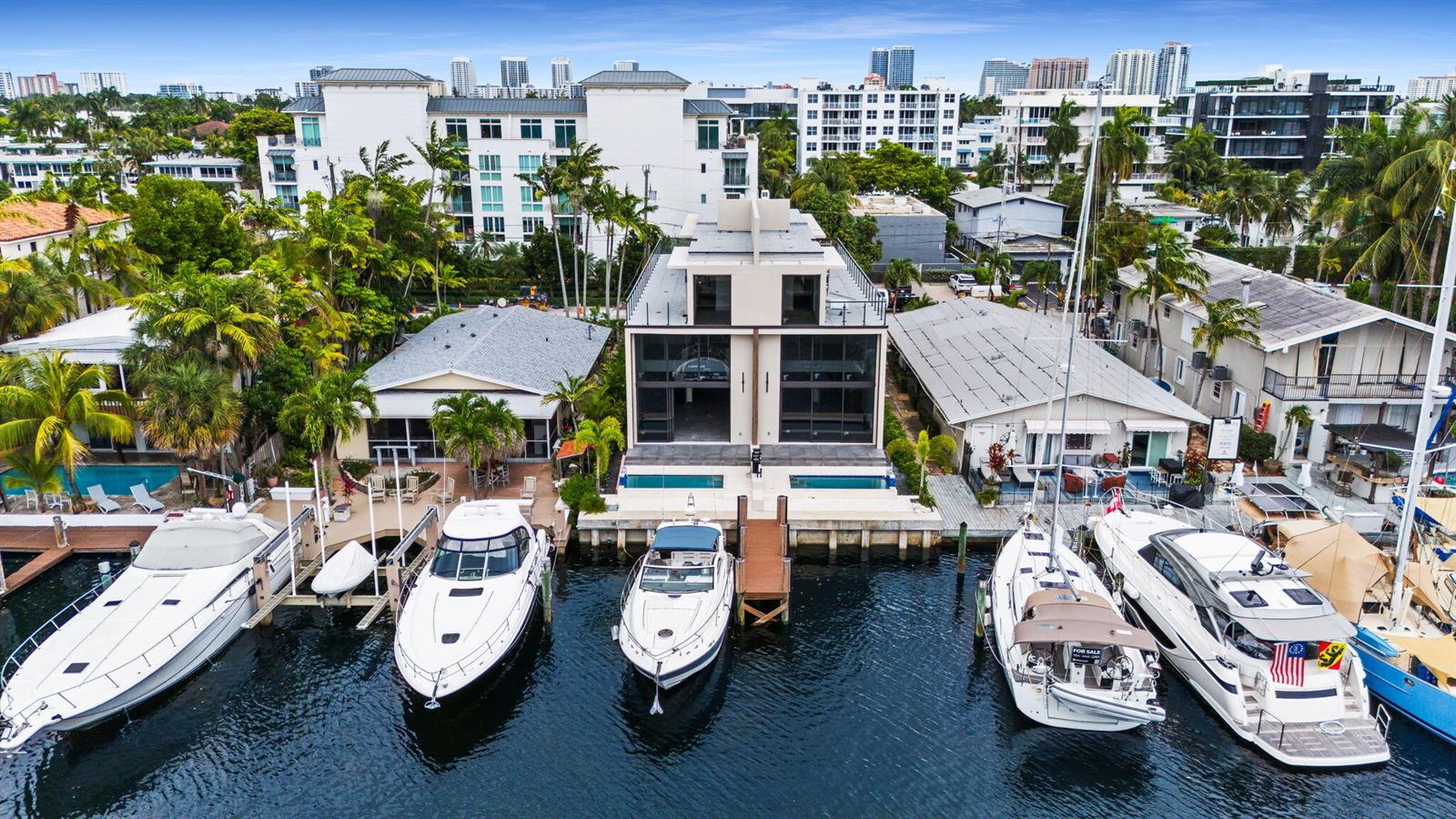 An aerial view of a modern waterfront home flanked by two houses and several docked boats — 321 Hendricks Isle, Fort Lauderdale FL 33301, FORT LAUDERDALE, FL