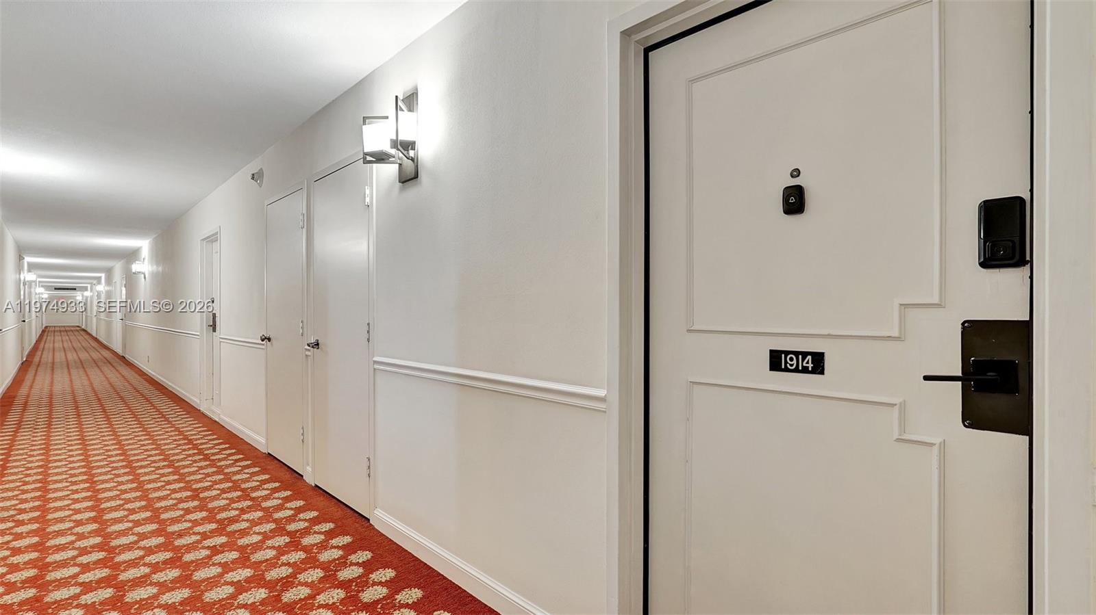 A long apartment hallway features white walls, a patterned red carpet, and unit 1914 — 2500 Parkview Dr # 1914, Hallandale Beach FL 33009, HALLANDALE BEACH, FL