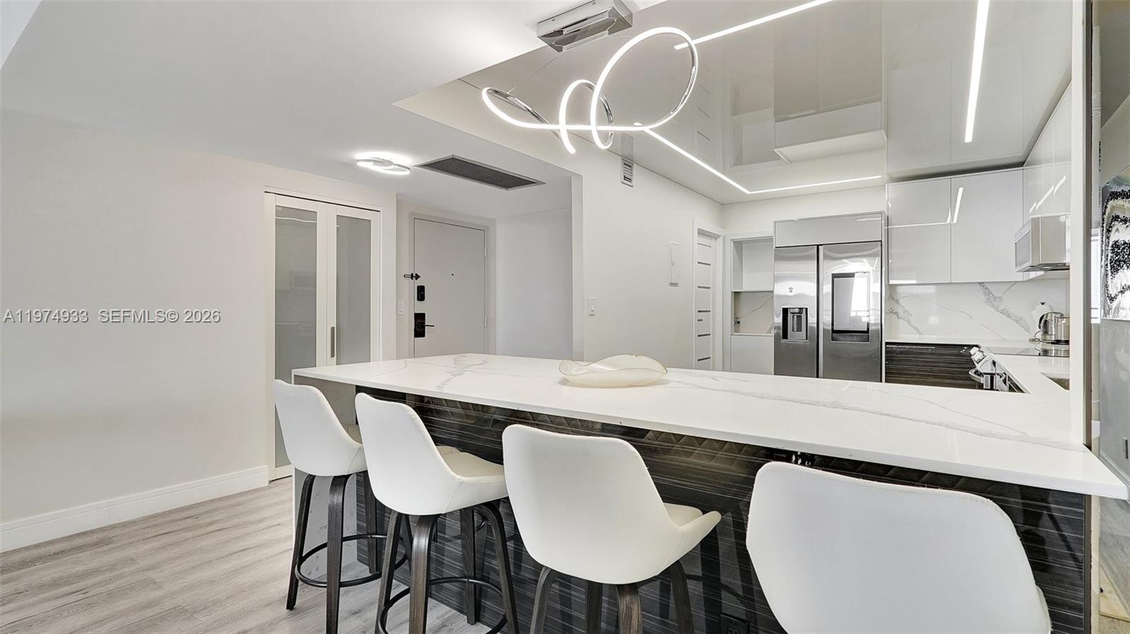 A modern kitchen features a white marble breakfast bar with four white bar stools — 2500 Parkview Dr # 1914, Hallandale Beach FL 33009, HALLANDALE BEACH, FL
