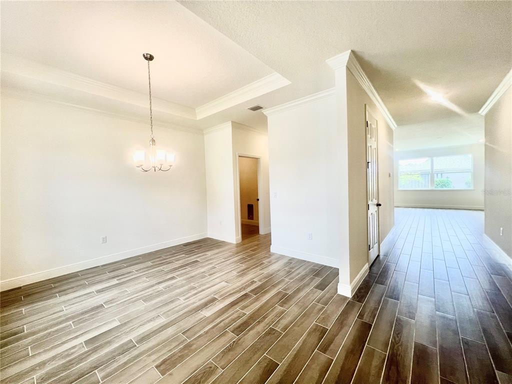 A dining area with a tray ceiling and chandelier features wood-look tile flooring throughout — 101 PRITCHARD DRIVE, PALM COAST, FL
