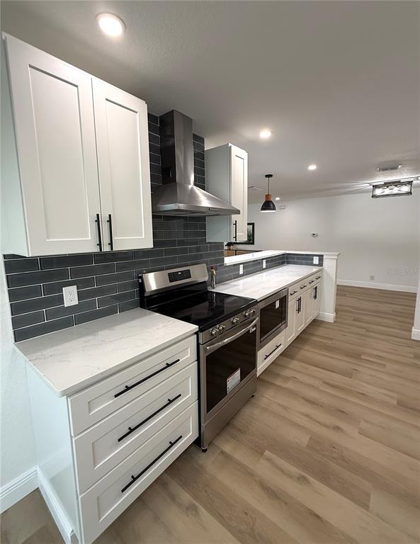 A modern kitchen features white cabinets, quartz countertops, dark subway tile backsplashes, and stainless appliances — 9124 39TH LANE N, PINELLAS PARK, FL