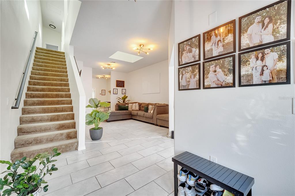 A bright entryway leads to a living room with tiled floors and a carpeted staircase — 1028 UNIVERSAL REST PLACE, KISSIMMEE, FL