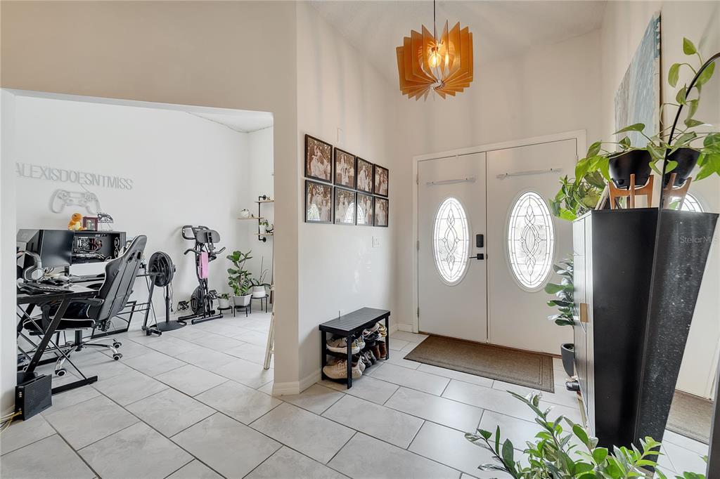 A tiled entryway features a double front door, a shoe rack, and an adjacent office area — 1028 UNIVERSAL REST PLACE, KISSIMMEE, FL