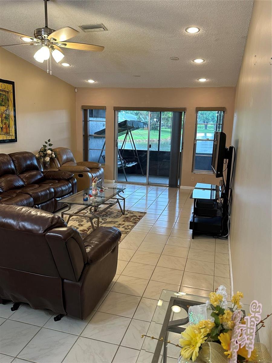 A living room with tile floors, leather furniture, and a sliding door to a patio — 8885 Windtree Street # D, Boca Raton FL 33496, BOCA RATON, FL