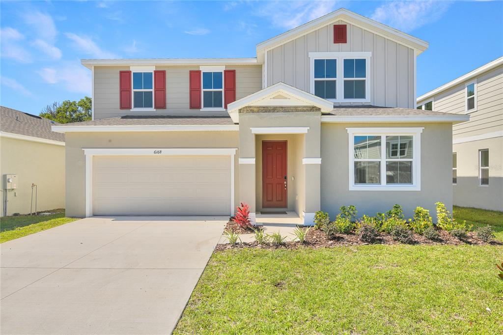 A two-story suburban house features a tan exterior, red shutters, and a two-car garage — 6168 SW 64TH TERRACE, OCALA, FL