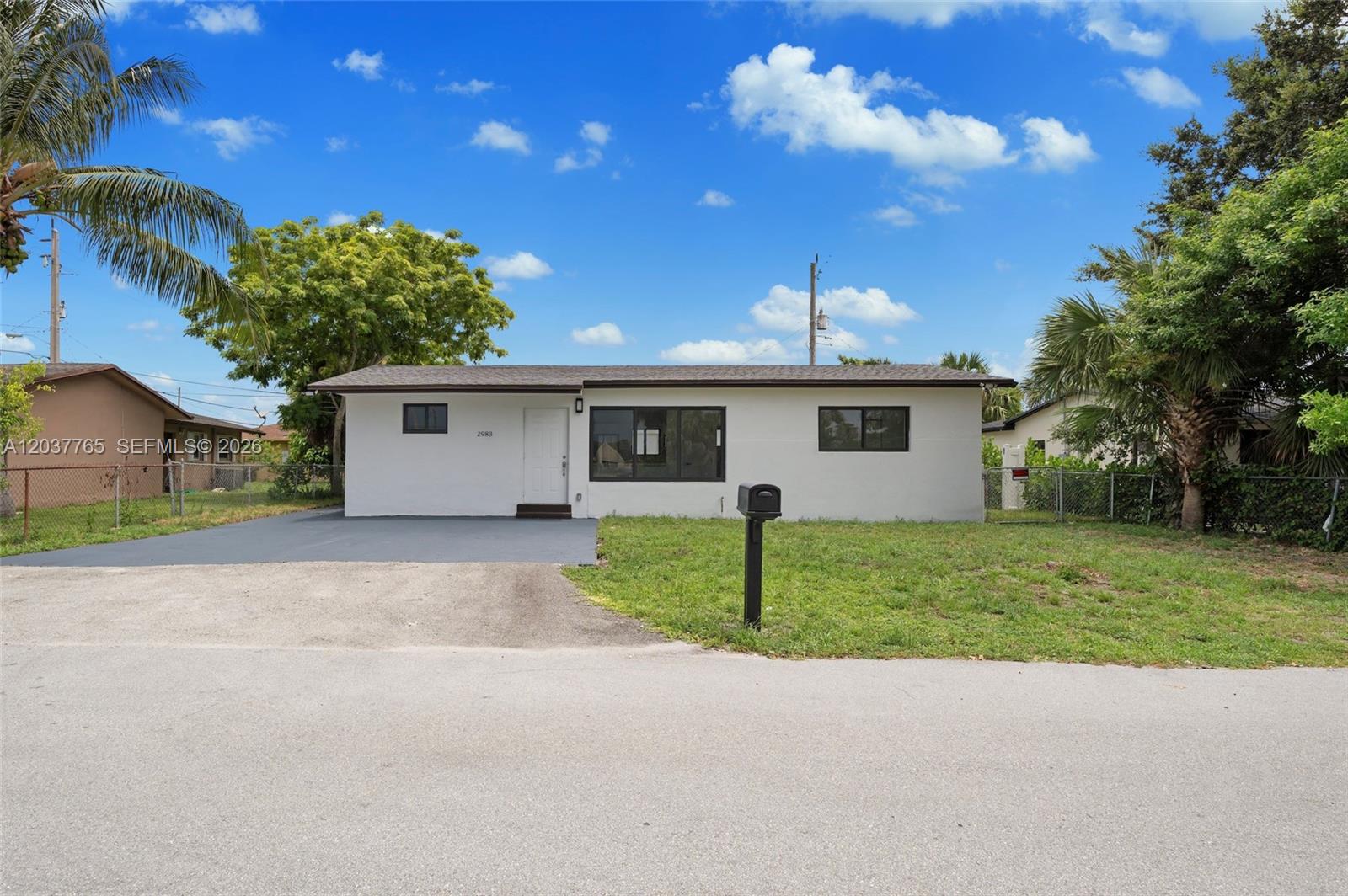 The exterior of a single-story white house features a gray driveway and a front lawn — 2983 NW 1st St, Pompano Beach FL 33069, POMPANO BEACH, FL