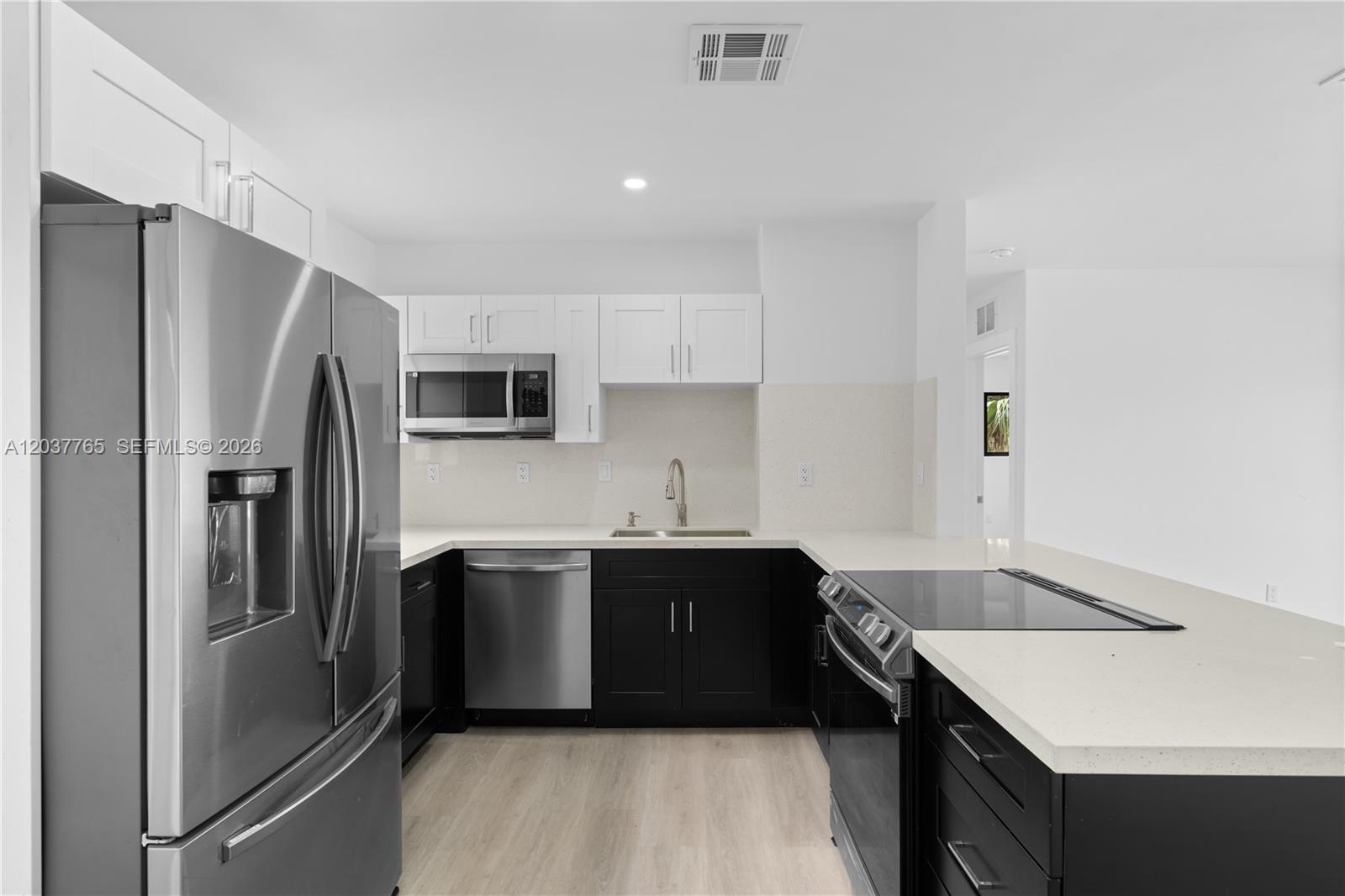 A kitchen features white upper cabinets, black lower cabinets, stainless steel appliances, and quartz countertops — 2983 NW 1st St, Pompano Beach FL 33069, POMPANO BEACH, FL