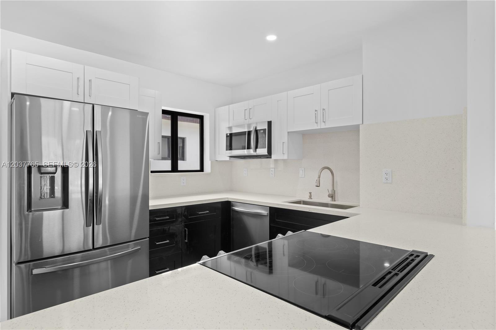 A kitchen features white upper cabinets, black lower cabinets, stainless steel appliances, and quartz countertops — 2983 NW 1st St, Pompano Beach FL 33069, POMPANO BEACH, FL