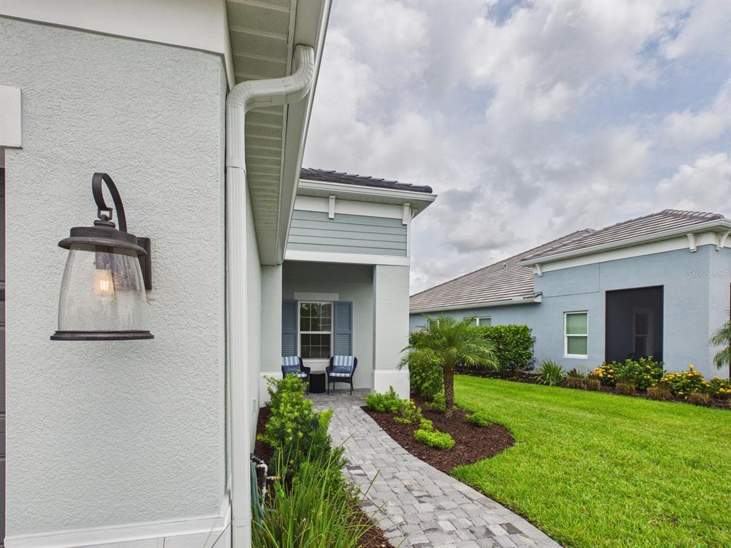 A light-colored house exterior features a covered entryway, a palm tree, and landscaped garden beds — 10012 LAKE WALES CIRCLE, SARASOTA, FL