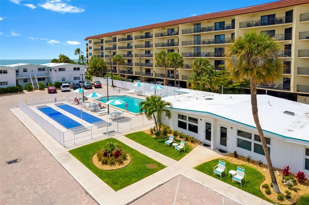 An aerial view shows a swimming pool, a shuffleboard court, and a multi-story apartment building — 6334 MIDNIGHT PASS ROAD UNIT 41, SARASOTA, FL
